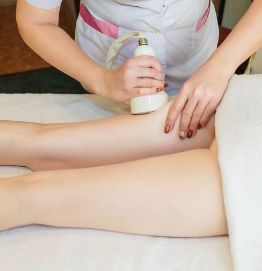 esteticista aplicando masaje en muslos de mujer 